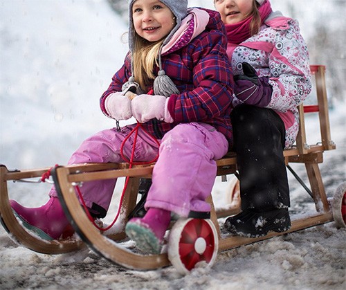 Schlittenfahren im Schnee mit Schlitten aus Holz